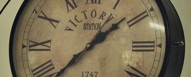 Antique clock face with Roman numerals reading Victoria Station, 1747 London.